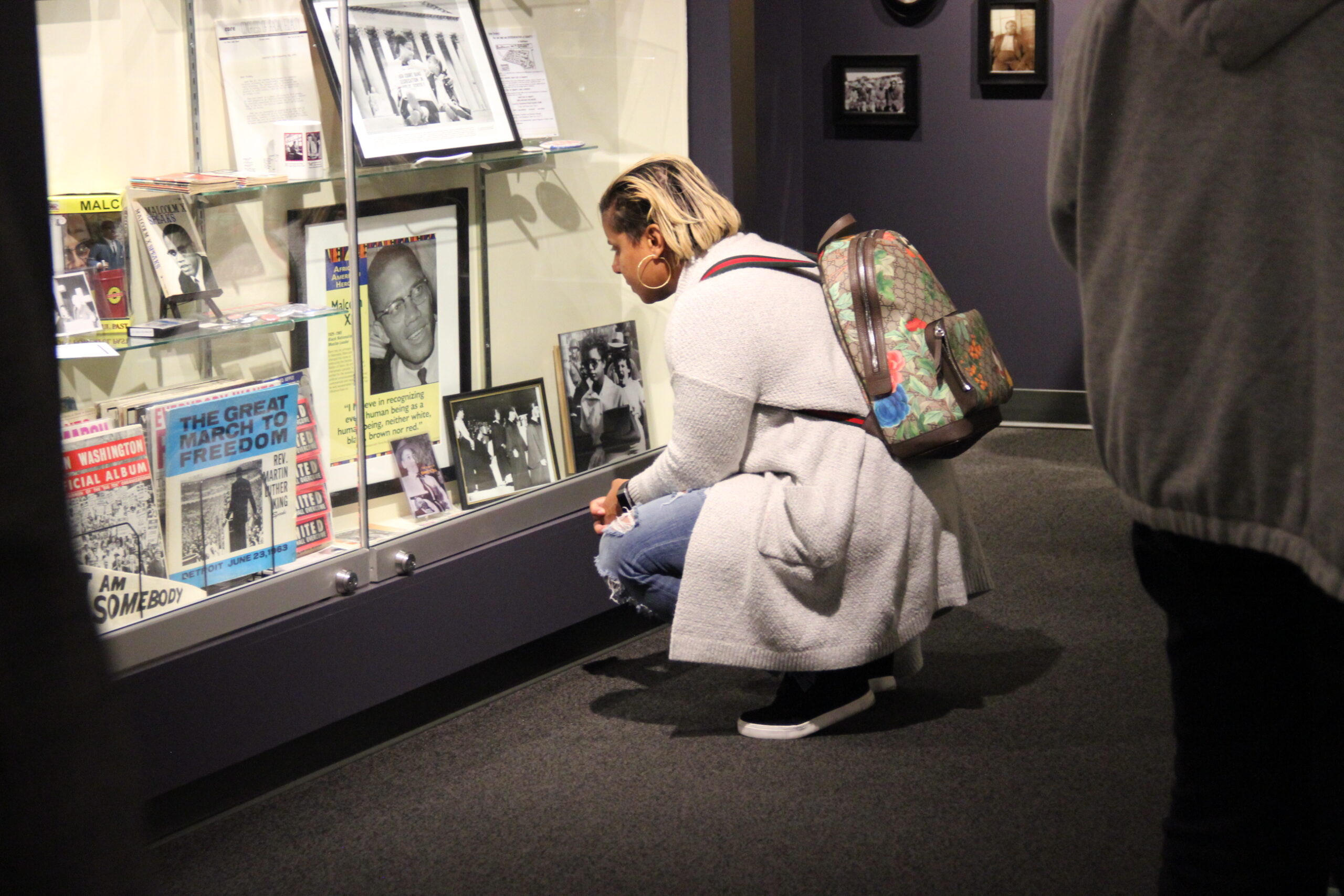 A visitor crouching down to look inside a display case at the Jim Crow Museum.